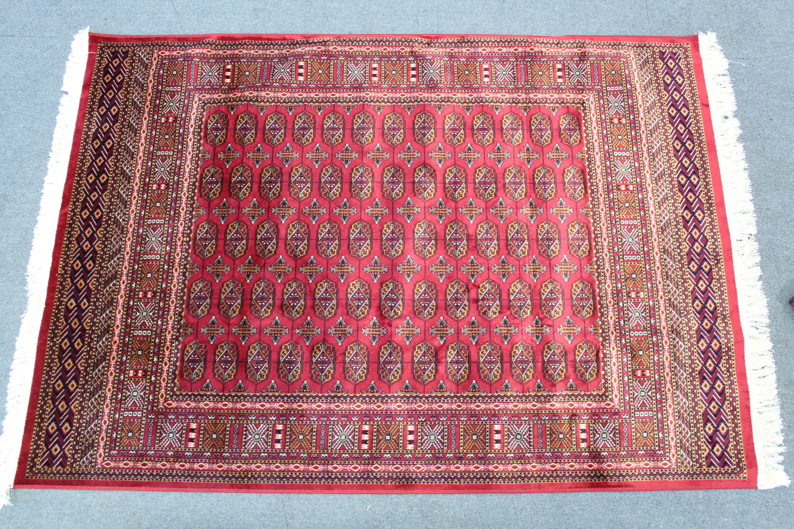 A Bokhara rug of crimson ground with five rows of thirteen guhls to centre within a wide border, 76”