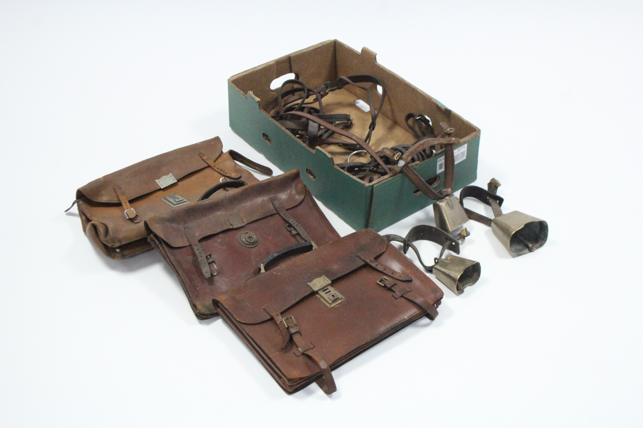 Three brass cowbells; various leather horse straps; & three leather briefcases.