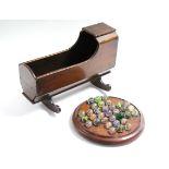 A 19th century mahogany miniature cradle, 14” long (w.a.f.); & a solitaire board with marbles.