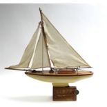 A 1960’s painted wooden pond yacht “Lloyd I”, with sails & stand, 22½” wide.