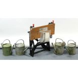 A black & Decker “workmate” & four galvanised metal watering cans.