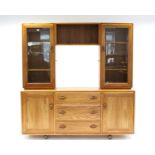 AN ERCOL LIGHT ELM SIDEBOARD the upper part with open shelf to centre flanked by glazed cabinet to