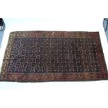 A Persian pattern rug of rust & blue ground & with all-over repeating geometric design to border