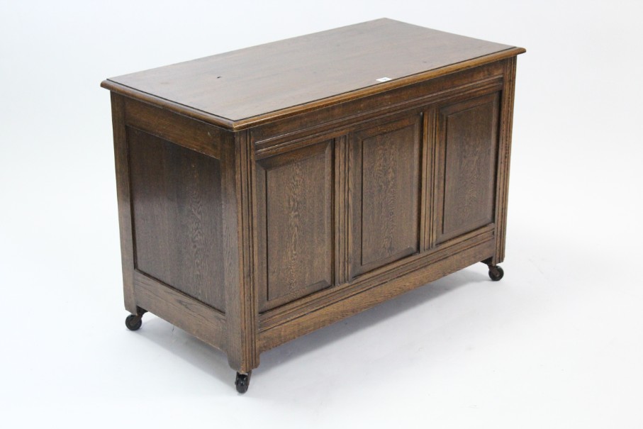 An oak coffer with hinged lift-lid, & with panelled front & sides, 37” long.
