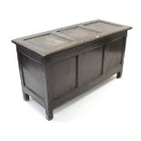 An antique oak coffer with panelled hinged lift-lid, front & sides, & on short square legs, 51¾”