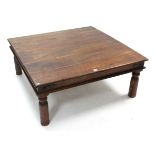 A large teak iron-bound square low coffee table on four turned legs, 43½” wide.