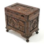 An eastern small carved camphor wood trunk with hinged lift-lid & on short cabriole legs & claw