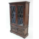 An oak bookcase with two adjustable shelves, enclosed by pair of leaded glazed doors above