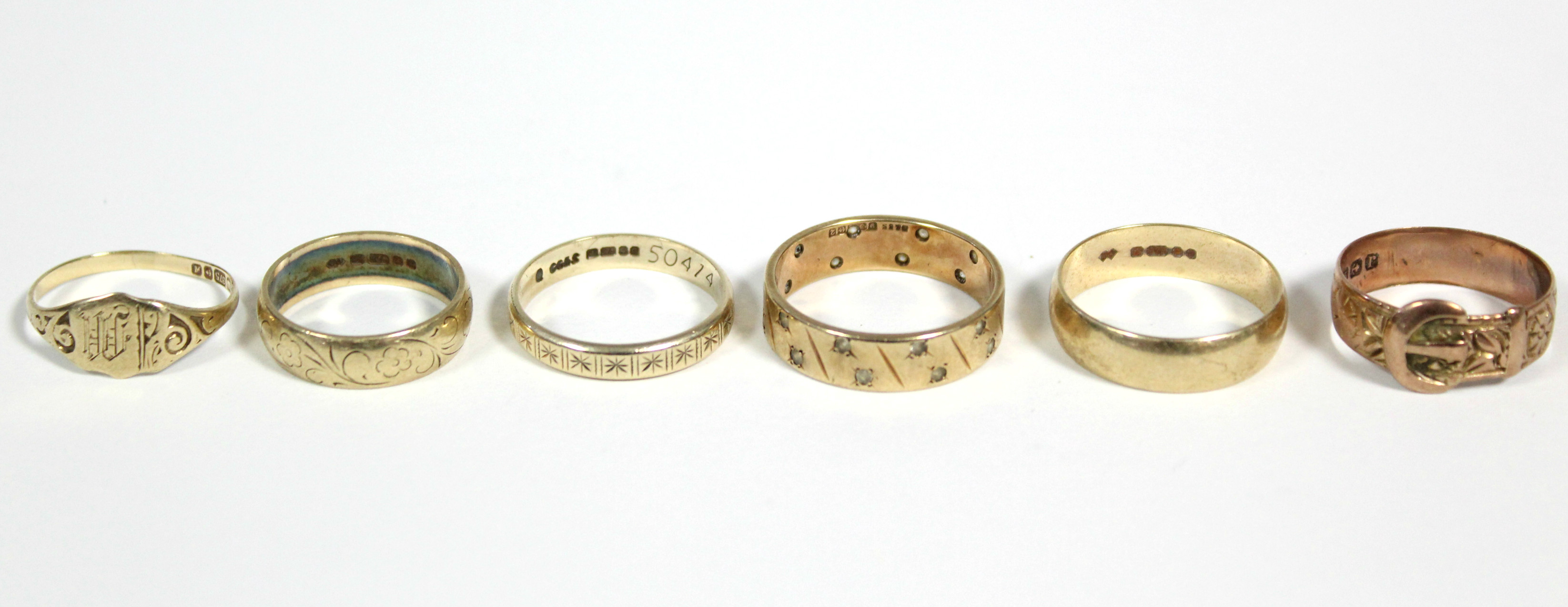 A 9ct. gold engraved belt buckle ring; a 9ct. engraved signet ring; two ditto engraved bands; a