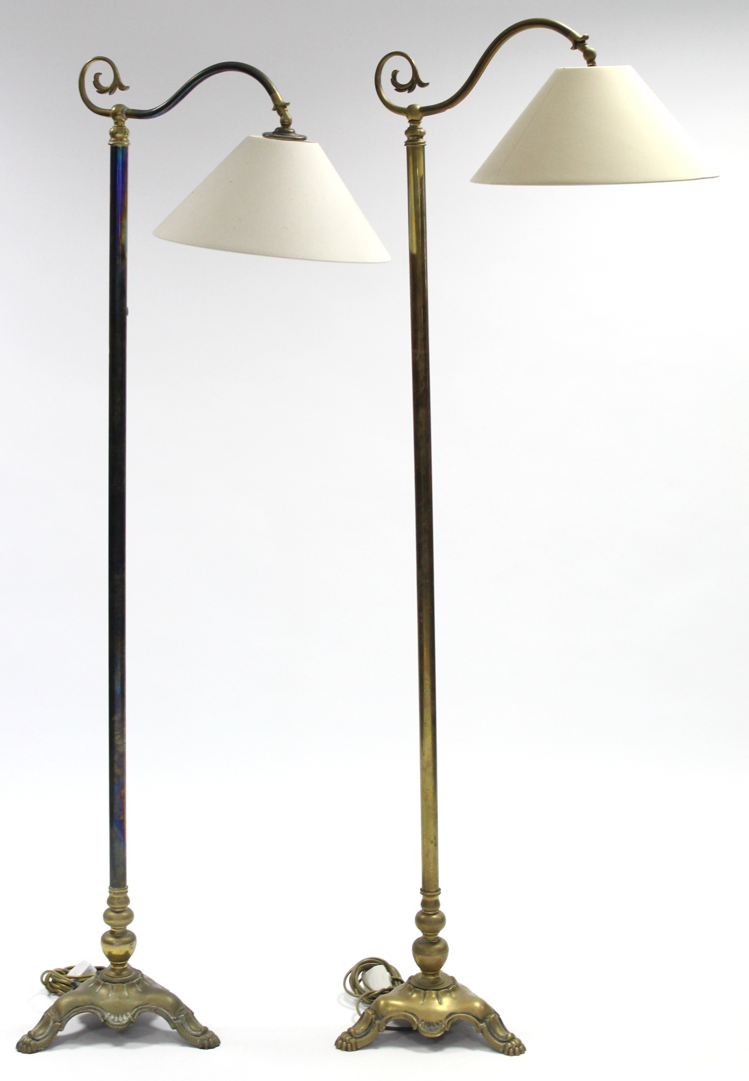 A pair of Edwardian-style brass standard lamps, each with foliate scroll arm on turned centre column
