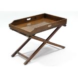 A 19th century mahogany butler's tray with pierced side handles, on plain folding trestle stand; 29"