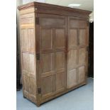 An early 18th century style oak wardrobe in two sections, with moulded cornice, enclosed pair of