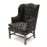 An 18th century style wing-back armchair upholstered deep blue floral material, the sprung seat with