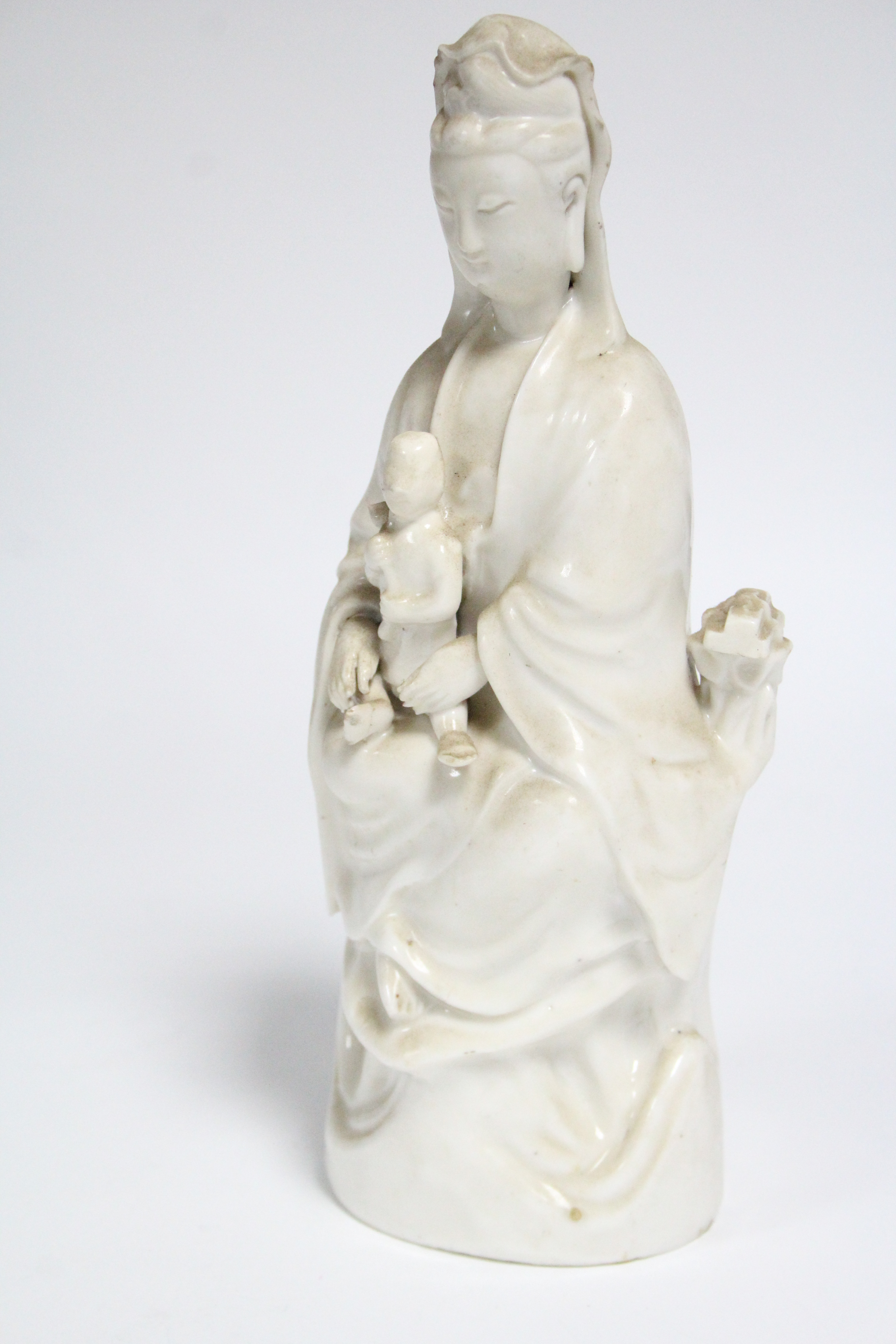 An 18th century Chinese blanc-de-chine figure of Guanyin, seated, with an infant on her lap; 10” - Image 2 of 4