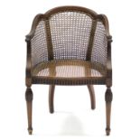 An Adam-style mahogany frame bergére with shaped rounded cane back & seat, the carved scroll arms