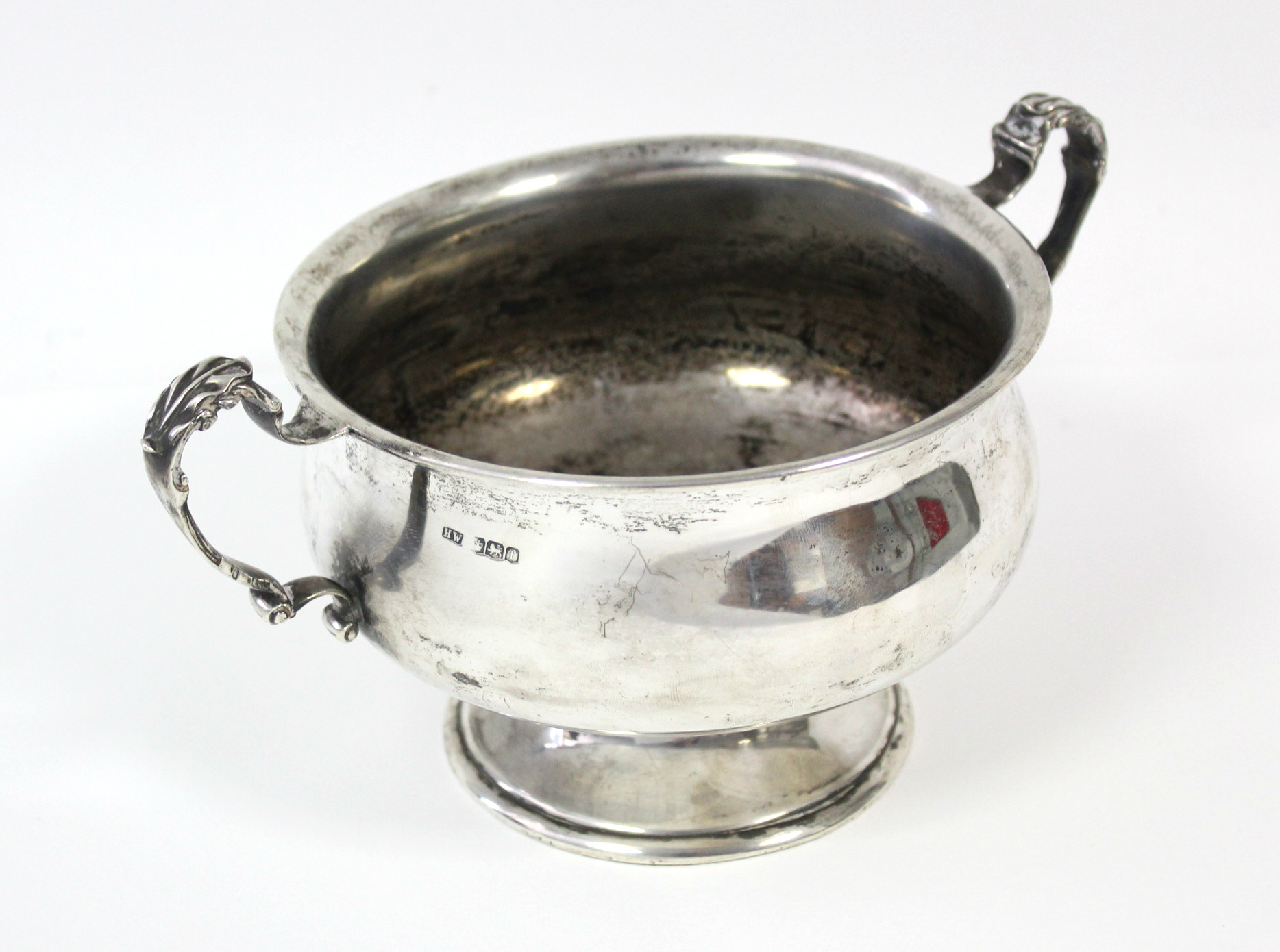 A George V silver two-handled bowl of squat baluster form, with leaf-scroll handles, & on pedestal