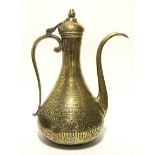 An eastern brass coffee pot of slender baluster form, with hinged lid, scroll handle, & all-over