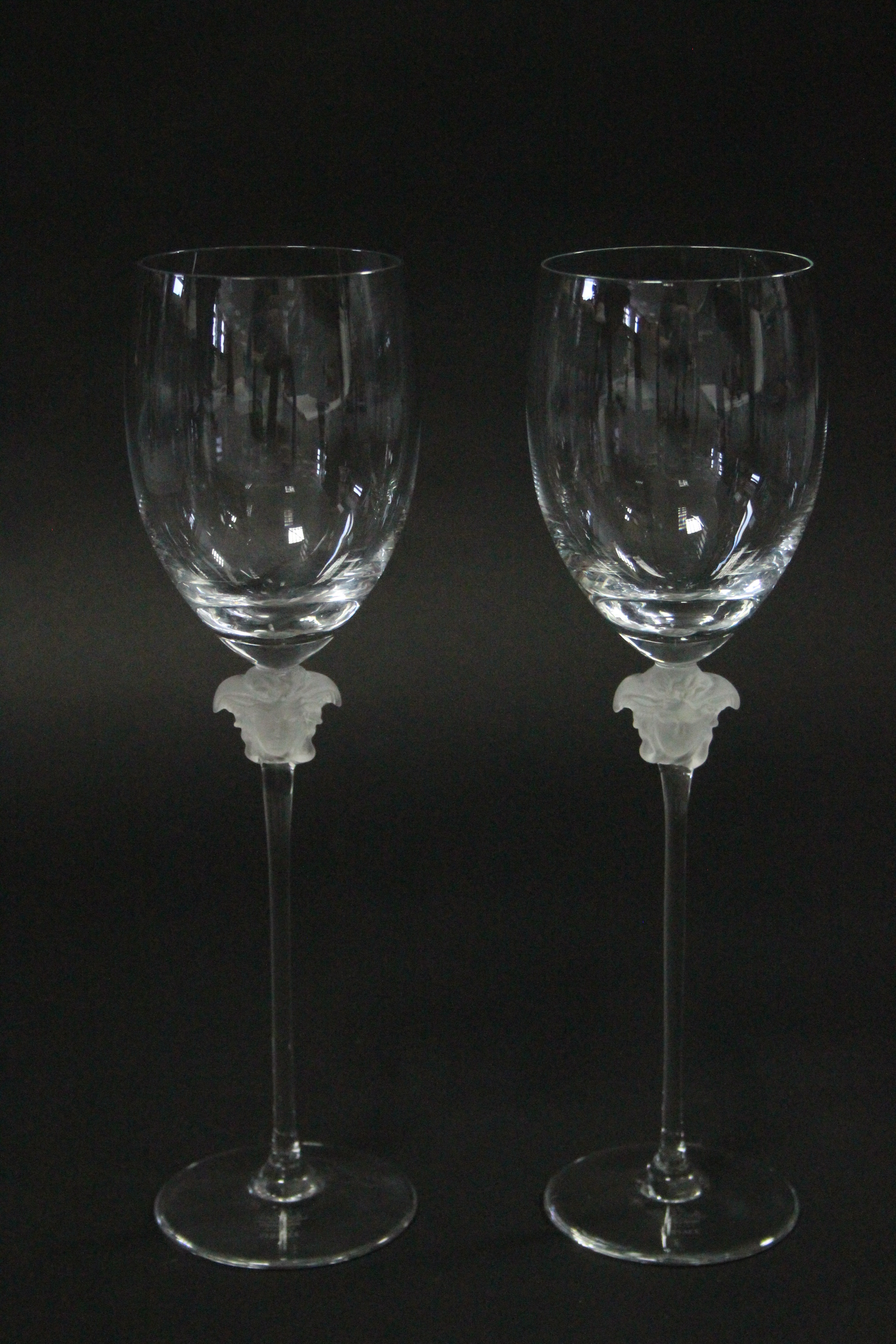A pair of Rosenthal “Versace” wine glasses, each with opalescent figure-head to the stem; 11¾”