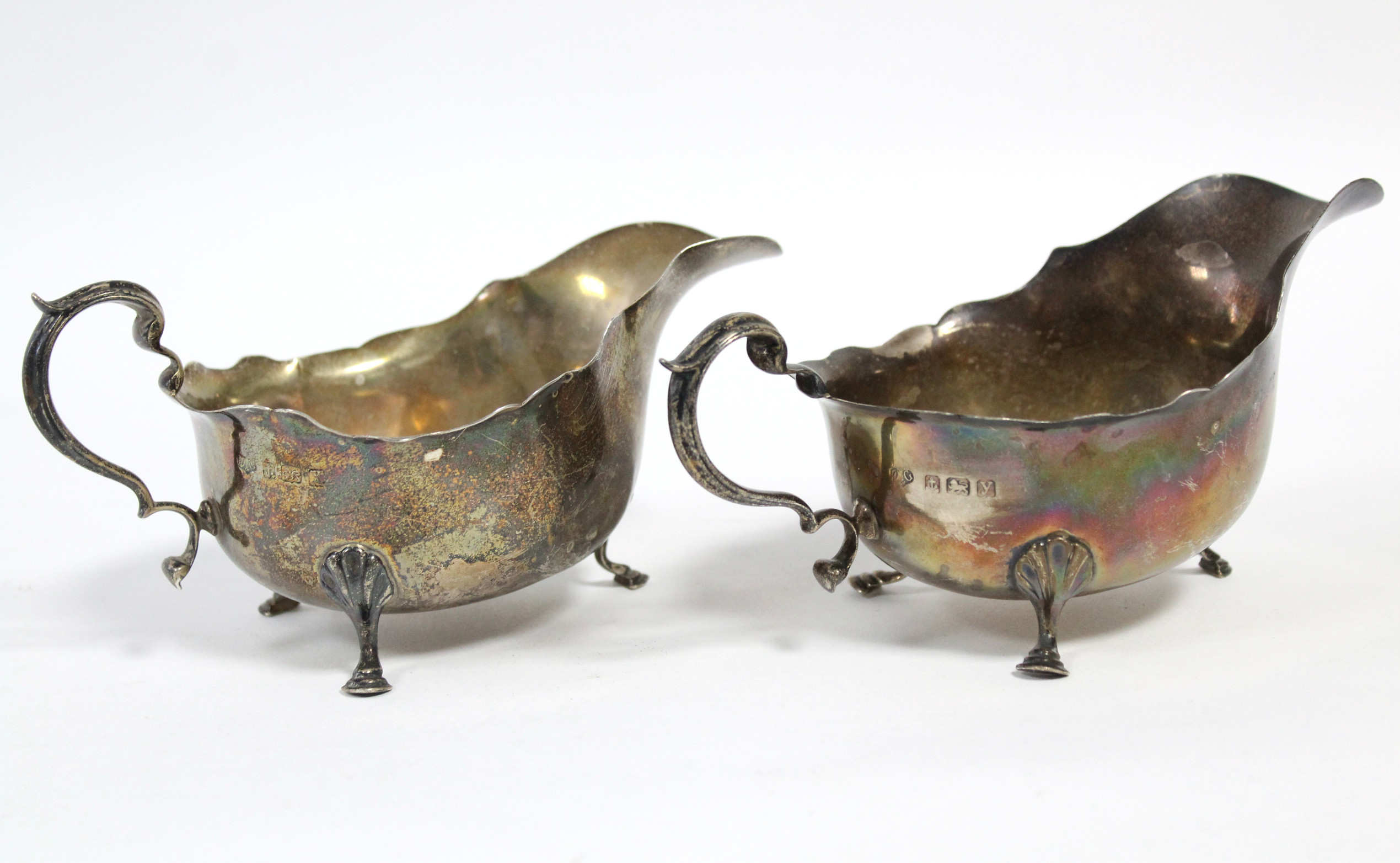 A pair of 18th century style silver oval sauce boats, each with cut-card rim, scroll handle & on