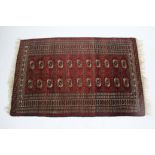 A Bokhara rug of crimson & ivory ground, with two rows of eleven guhls within multiple geometric