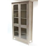 A Marks & Spencer bleached pine tall cabinet, fitted four shelves enclosed by pair of glazed