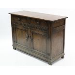 A reproduction oak sideboard, fitted two frieze drawers above cupboard enclosed by pair of panel