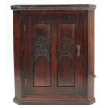 A carved oak hanging corner cupboard, fitted centre shelf enclosed by panel door, 26½" wide x 31"