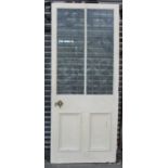 An early 20th century white painted wooden exterior door, inset two leaded glazed panels above a