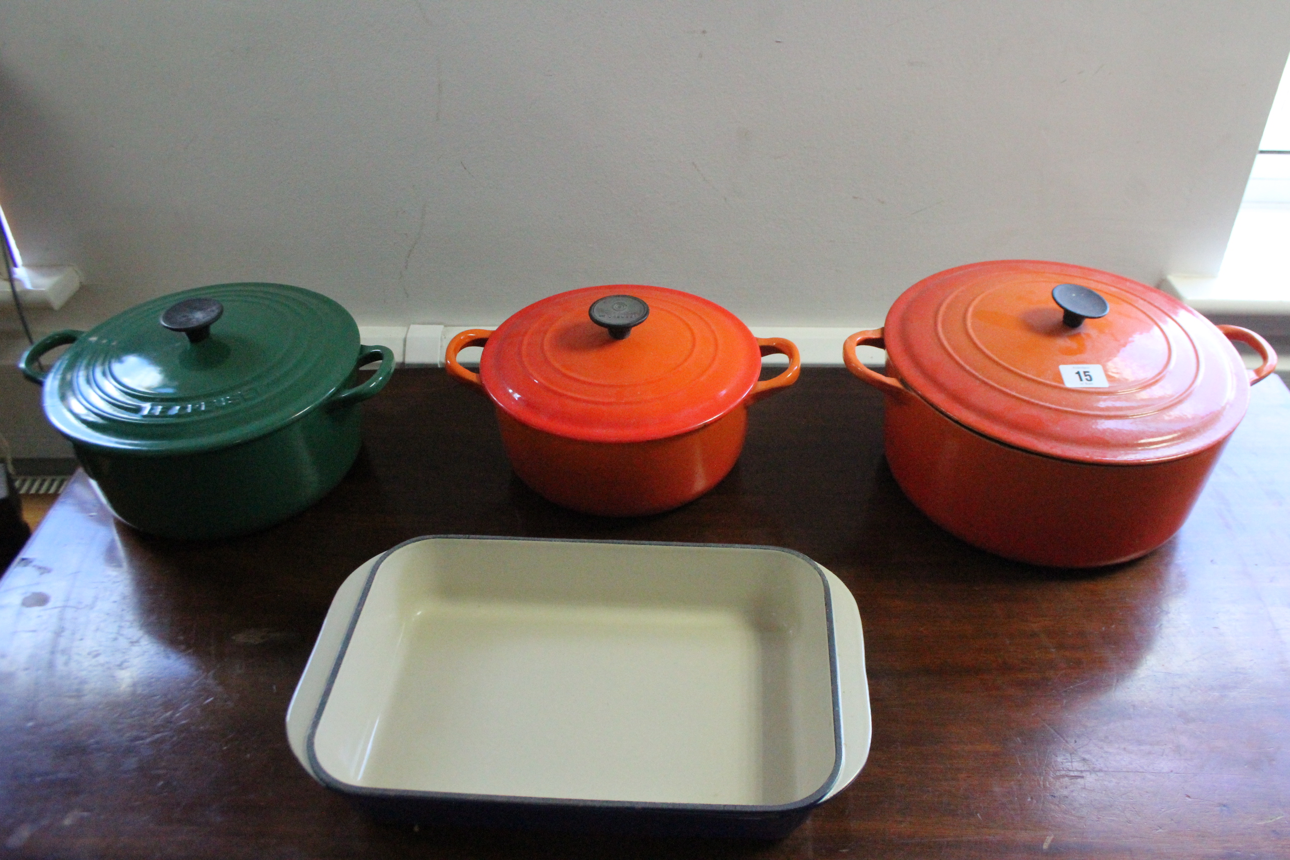 Two Le Creuset orange enamelled cooking pots, & a green glazed ditto.