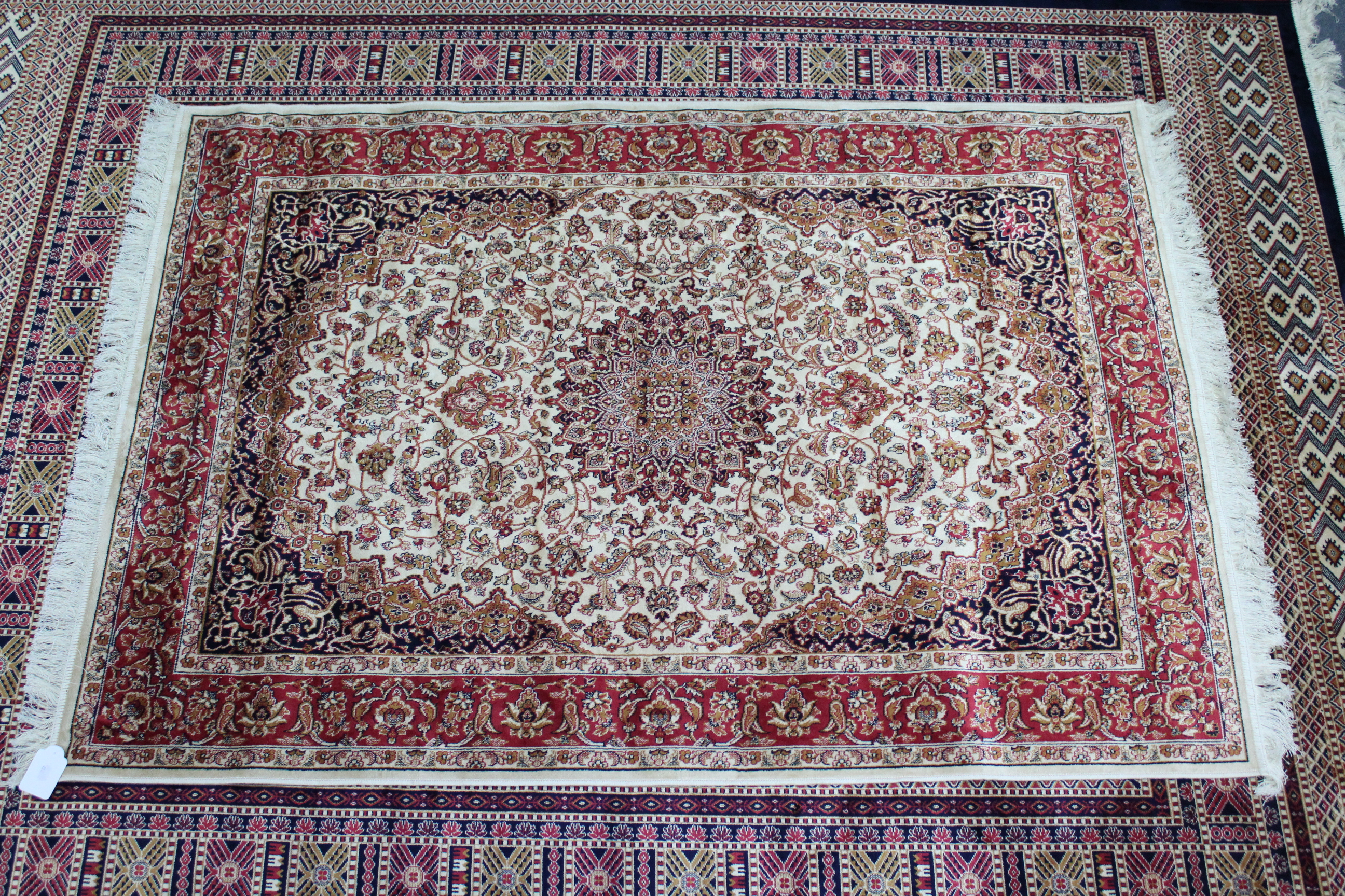 A Keshan rug of ivory & crimson ground & with all-over repeating multi-coloured geometric design,