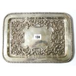 An Edwardian silver rectangular tray with beaded edge & with embossed scroll design to centre,