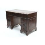 A reproduction mahogany pedestal desk, inset gilt-tooled brown leather cloth, fitted with an