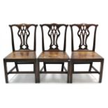 A set of three mahogany cottage dining chairs with pierced & shaped splat backs, hard seats, & on