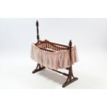 A late 19th/early 20th century oak rocking dolls crib, 33" long, complete with bedding.