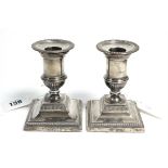 A pair of late Victorian silver dwarf candlesticks on loaded square bases, 4" high, London 1898.