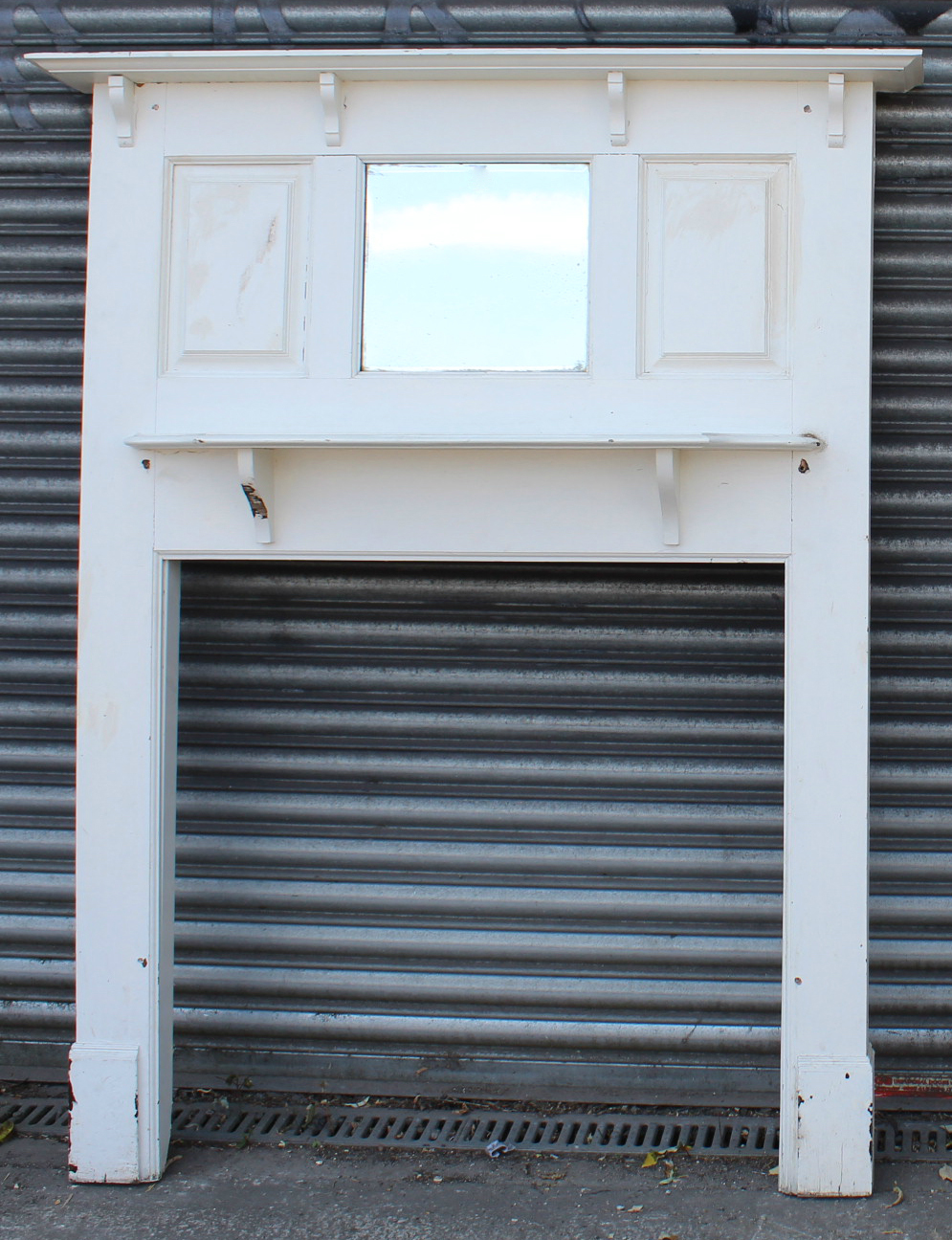 An early 20th century white painted wooden fire surround inset rectangular bevelled plate to