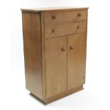 A limed oak millinery cupboard, fitted two long drawers above three shelves enclosed by pair of
