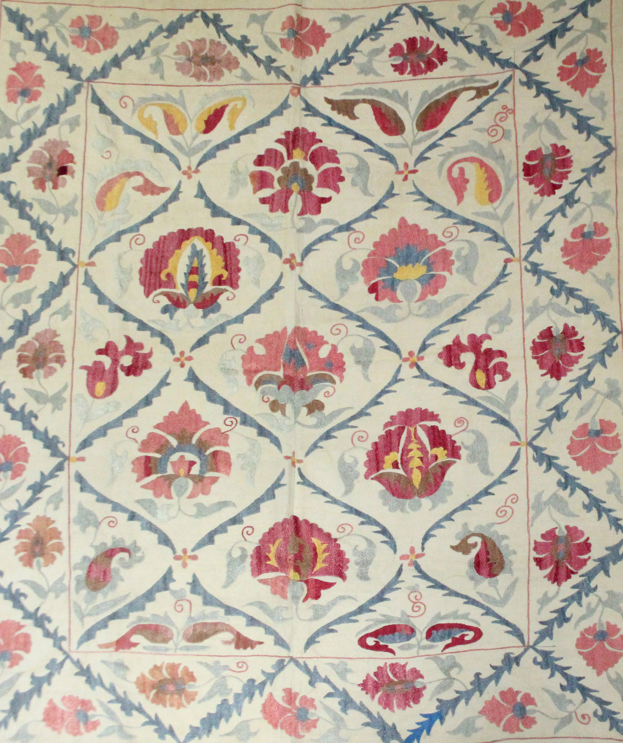 An Indian embroidered coverlet of cream ground, with multi-coloured stylised floral decoration,