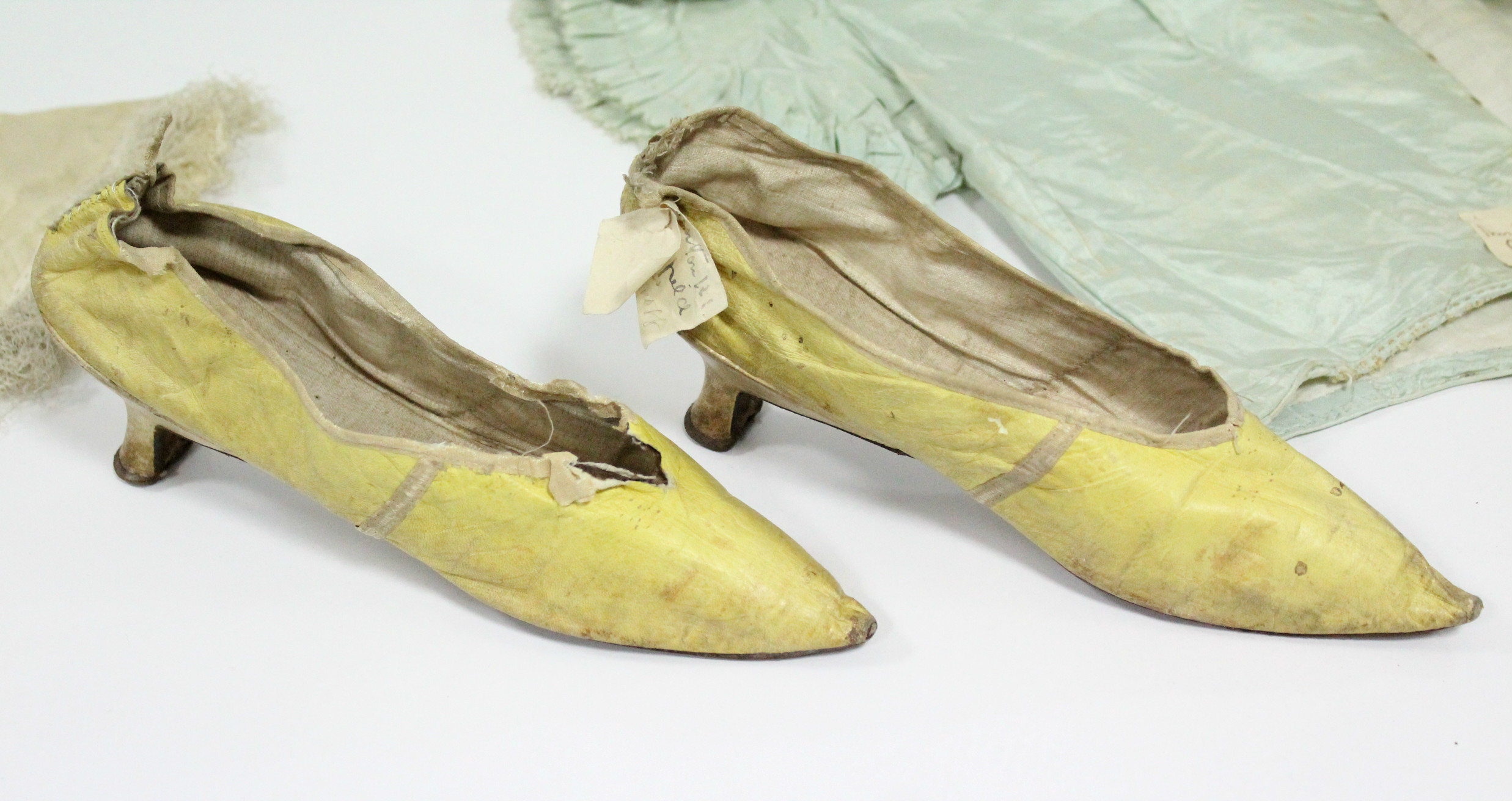 A pair of early 19th century yellow kid leather ladies shoes; & four early Victorian coloured silk