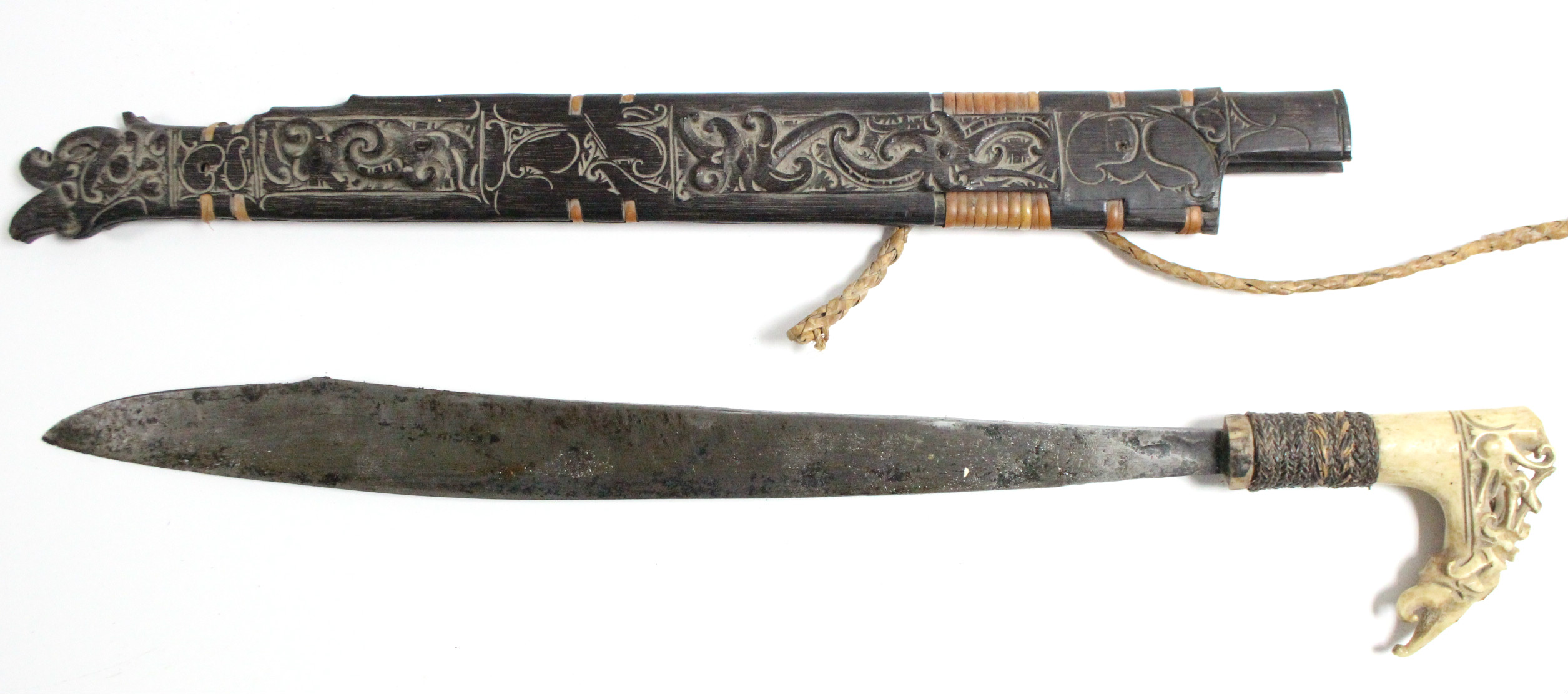 A Borneon ceremonial knife with 18½” long single-edge curved blade, with carved bone handle, &