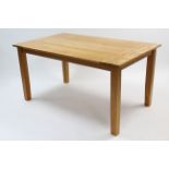 A light oak rectangular dining table on square tapered legs, 59¼” x 35½”.