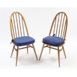 A pair of Ercol light elm dining chairs with spindles to the hooped backs, hard seats & on round