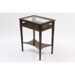 An Edwardian mahogany bijouterie table enclosed by glazed hinged lift-lid, with glazed sides, having