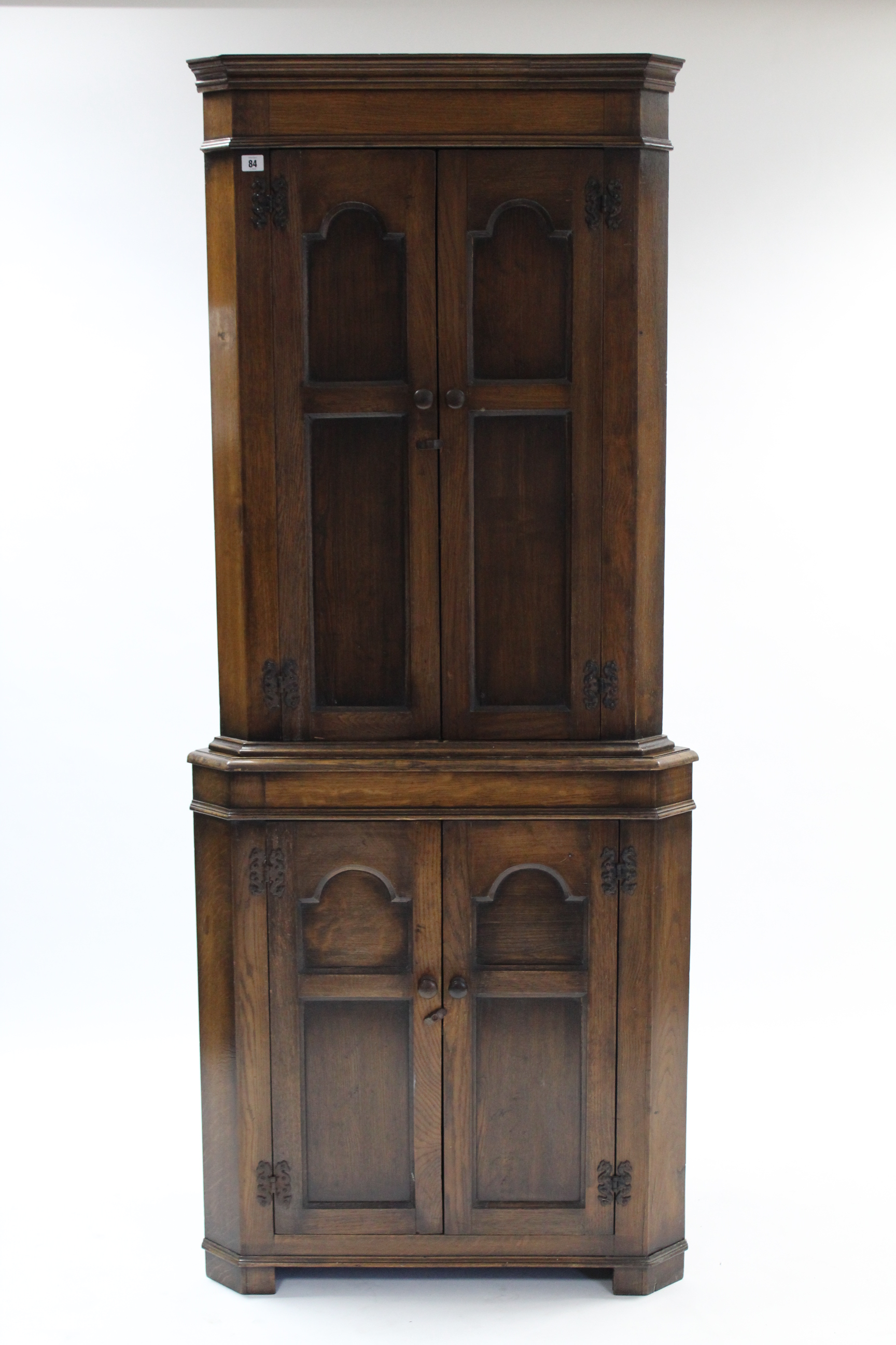 A reproduction oak tall standing corner cupboard, the upper part fitted two shaped shelves