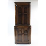 A reproduction oak tall standing corner cupboard, the upper part fitted two shaped shelves