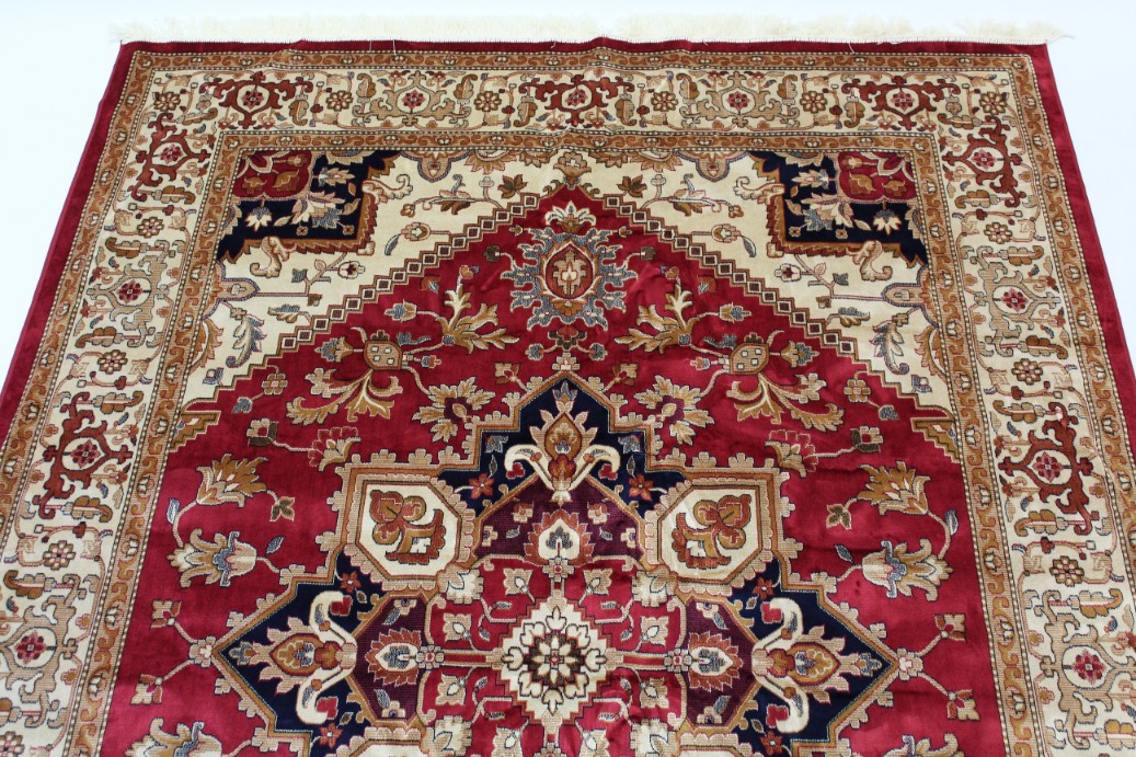 A Heriz carpet of crimson & ivory ground, with geometric design to centre within a wide border, 110”