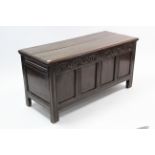 A 19th century oak coffer with hinged lift-lid, carved frieze, with panelled front & sides, & on