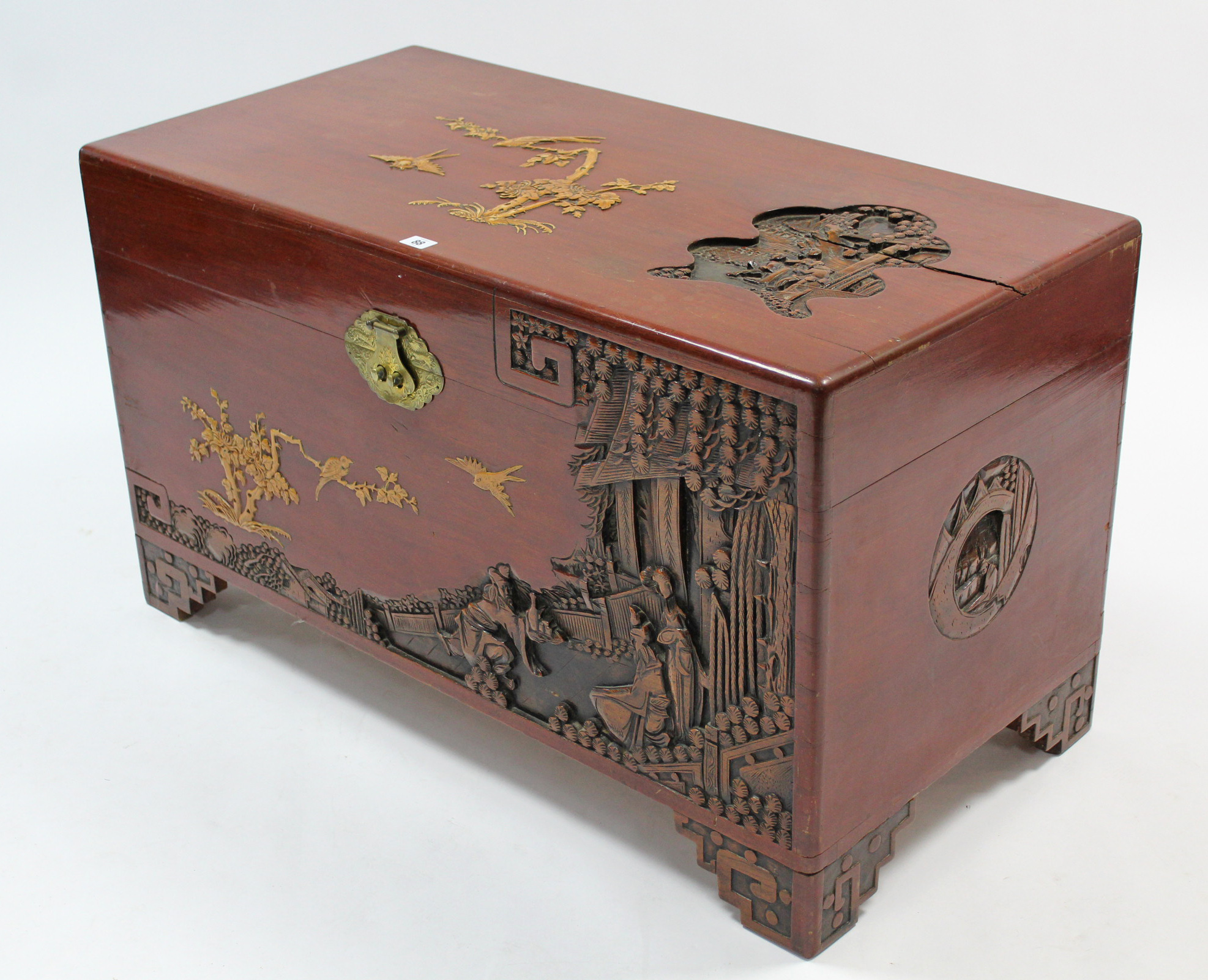 A Chinese camphor wood chest with carved figure scene decoration to the hinged lift-lid, front, &
