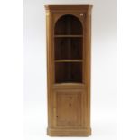 A pine tall standing corner cabinet, fitted two open shelves above cupboard enclosed by panel