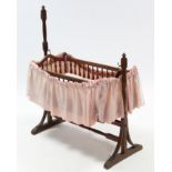 A late 19th/early 20th century oak rocking dolls crib, 33" long, complete with bedding.